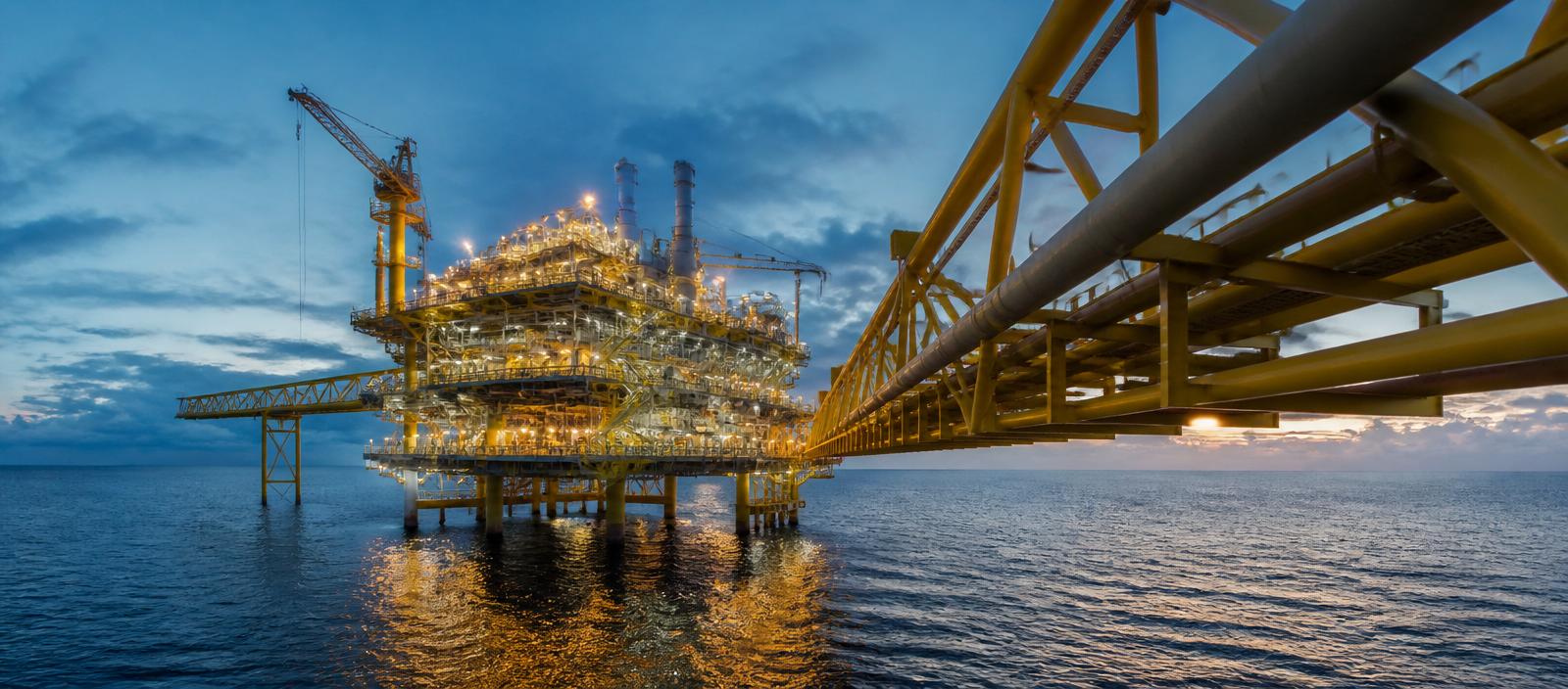Offshore oil and gas platform with pipeline infrastructure at dusk